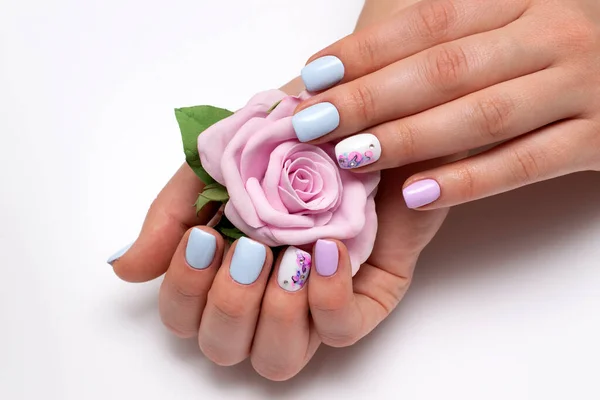 Wedding manicure with a pink rose in hands. Light blue, lilac, white manicure on short square nails with stains, abstraction, ink for nails, crystals. Bleached nameless nail.