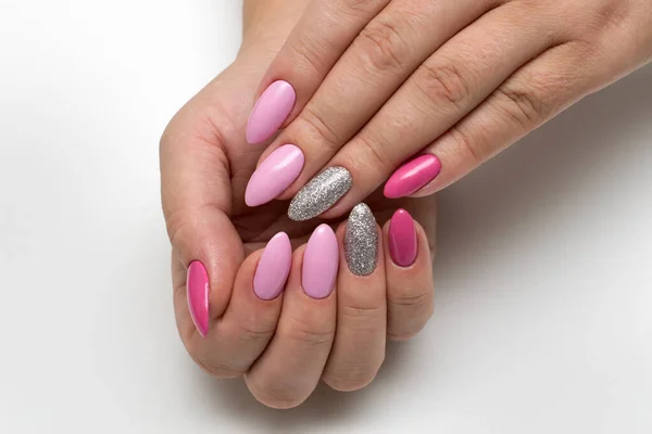 Manicure. Pink, dark pink manicure on long sharp notes with silver sparkles close-up on a white background.