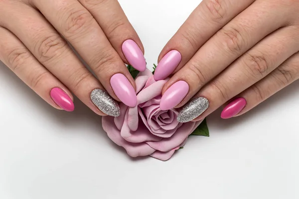 Manicure. Pink, dark pink manicure on long sharp notes with silver sparkles close-up on a white background with a pink rose in the palm.