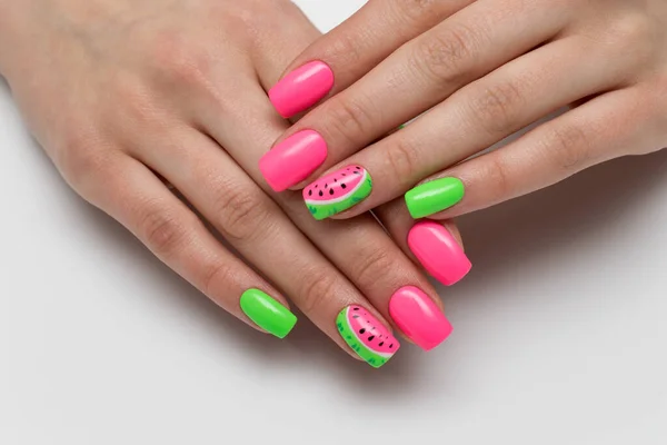 夏天粉红和浅绿色的指甲和漆过的西瓜 度假修指甲 白色背景的特写 指甲的酸颜色 厚重的钉子 图库图片