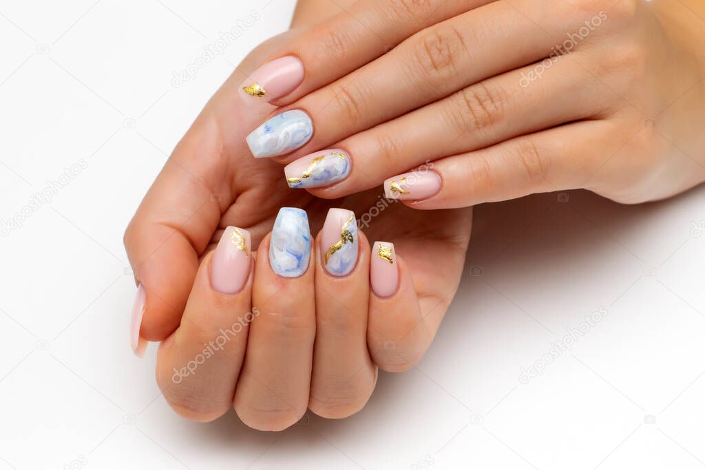 Nude, natural manicure with blue, white streaks and gold foil on long square nails. Gel nails. Heavenly manicure. Close-up on a white background.