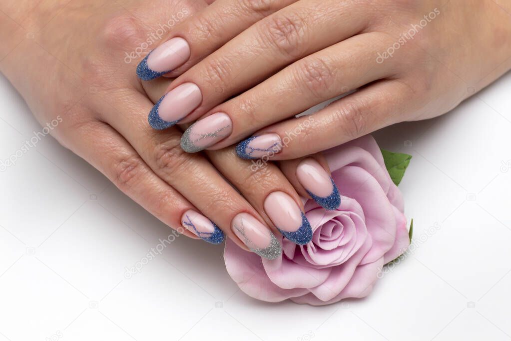 French blue, silver manicure on long oval nails with sparkles and stripes on a white background close-up