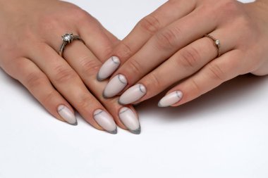 Düğün manikürü. Işıldayan gümüş uzun sivri tırnaklar. Beyaz arkaplanda yakın plan.
