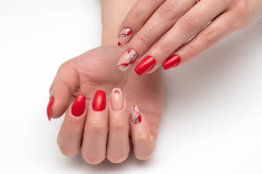Kalpli kırmızı, bej manikür, altın döküm, kırmızı çizgiler, beyaz arka planda uzun kare çivili dalgalar.