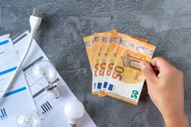 Elektrik faturasını ödemek için faturaları sayan kişi. Yüksek elektrik maliyeti kavramı. Alternatif enerji kullanımını kavra. 
