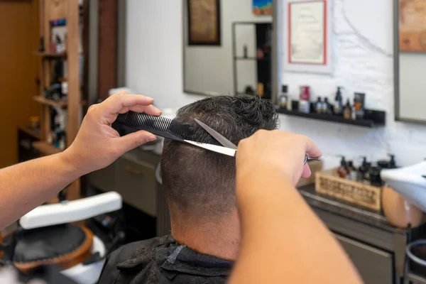 Primer plano de un corte de pelo realizado con tijeras por un peluquero a un cliente en una peluquería. Concepto de aseo masculino. — Foto de Stock