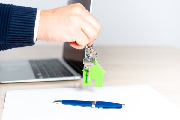Закрытие руки, вручающей ключи от нового дома после подписания договора купли-продажи дома.