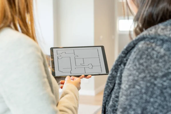 Bayan emlakçı müşterisine tablet aracılığıyla satılacak mülkün planlarını gösteriyor. Mülk satışı.