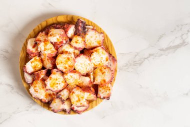 View from above of pulpo a la gallega, an octopus with boiled potatoes, typical Spanish Galician dish, on a traditional wooden plate, with copy space