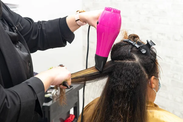 Peluquería estirar y secar el cabello de un cliente con el pelo dañado en un salón de belleza con un cepillo redondo. De cerca. Copiar espacio — Foto de Stock