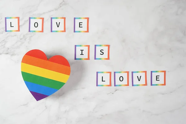 Cuore con colori LGBTQ con la frase Love is Love su uno sfondo di marmo. Tolleranza, diversità e inclusione dei concetti — Foto Stock