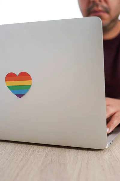 Nerozpoznatelný nerozpoznatelný hispánec pracující se svým počítačem, který má srdce s barvami LGBTQ. Koncept tolerance, inkluze a rozmanitosti. — Stock fotografie