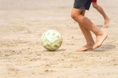 Çocuk kumsalda kumda futbol oynuyor. Tanınmayan insanlar. Yaz tatili kavramı. 