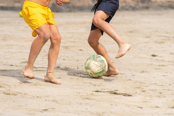 Children playing soccer on the beach sand enjoying the beginning of summer. Unrecognizable people. Summer vacation concept. — Stok fotoğraf