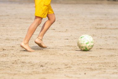 Çocuk kumsalda kumda futbol oynuyor. Tanınmayan insanlar. Yaz tatili kavramı. 