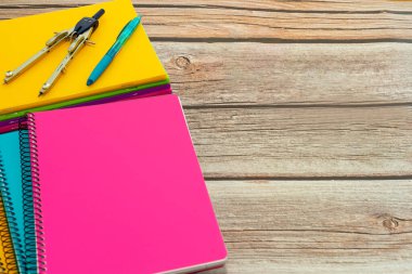 Several colored notebooks with compass and pen on wooden table. Back to class . High quality photo