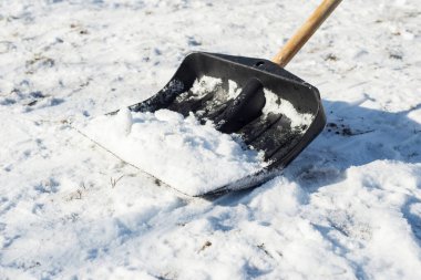 Şiddetli bir kar yağışı sonrası kırsalda siyah bir kürekle kar temizleme.