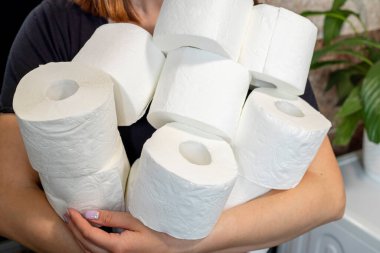 İnsanlar koronavirüs yüzünden evdeki karantina için tuvalet kağıdı stokluyorlar. Kadının elinde bir sürü tuvalet kağıdı var..