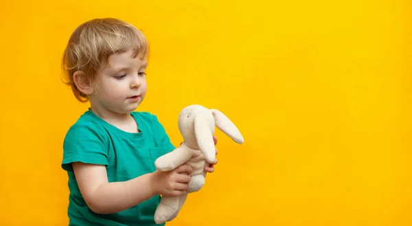 Lindo Niño Pequeño Abrazando Juguete Conejo Felpa Sobre Fondo Amarillo — Foto de Stock