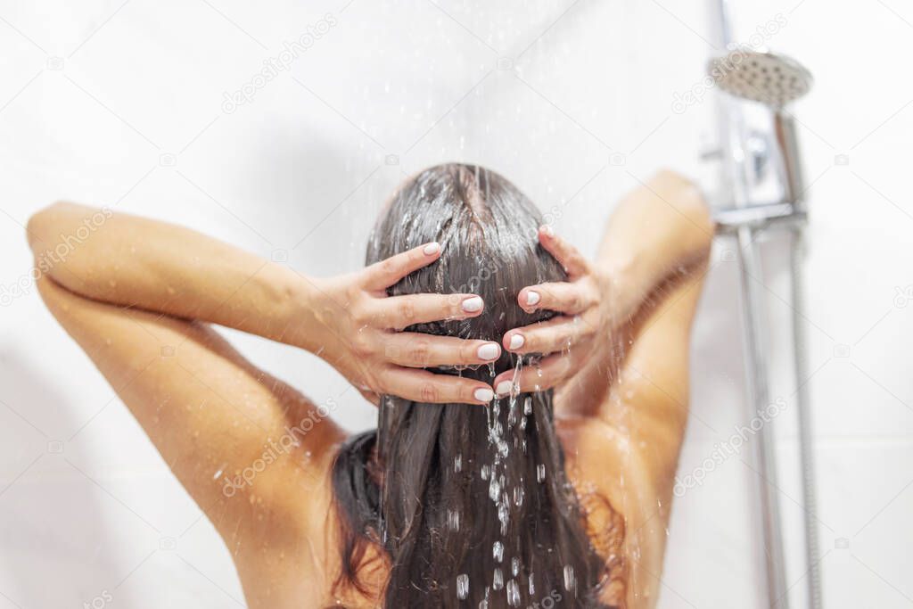 Young woman washing hair in shower at home, back view. Healthy lifestyle.
