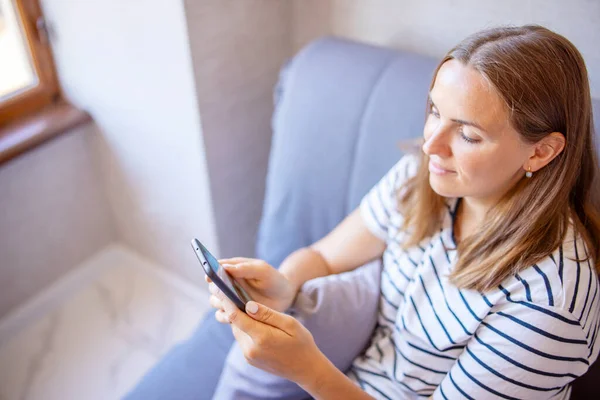 Jovem Feliz Está Usando Telefone Celular Enquanto Está Sentado Sofá — Fotografia de Stock