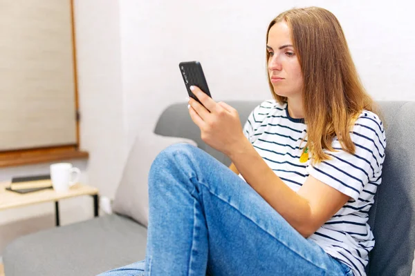 Femeie Tânără Fericită Folosește Telefonul Mobil Timp Stă Canapea Acasă — Fotografie, imagine de stoc