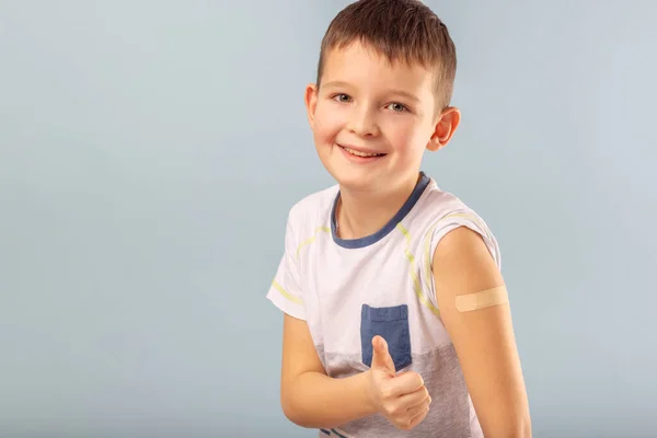 Aşılanmış çocuk baş parmağıyla işaret ediyor, Coronavirus aşısı aşısından sonra alçıyla elini gösteriyor. Çocuklar ve gençler için aşı kampanyası başlatıldı. Başarılı Covid-19 aşısı.