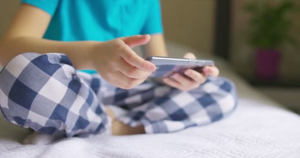 孩子们一边坐在床上一边用智能手机 一边上网浏览 一边用智能手机聊天 与父母或朋友交流 — 图库视频影像
