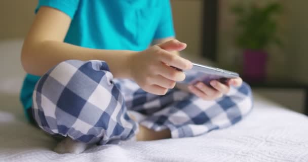 孩子们一边坐在床上一边用智能手机 一边上网浏览 一边用智能手机聊天 与父母或朋友交流 — 图库视频影像
