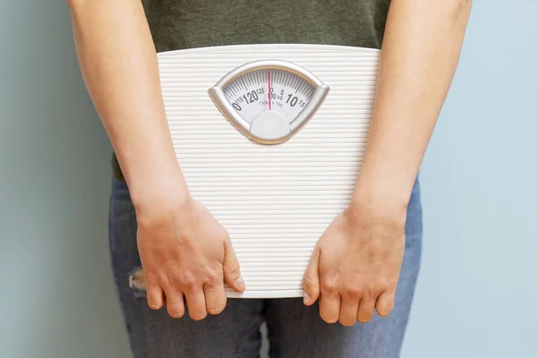 Young woman holding white scales to check the results of her diet . Diet and sport concept.