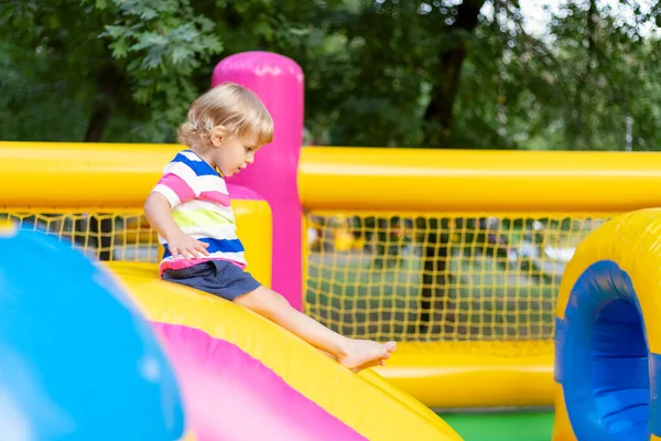 Mutlu çocuklar renkli şişme eğlence parkında eğleniyorlar. Çocuklar eğlenir ve açık alanda oyun oynarlar..