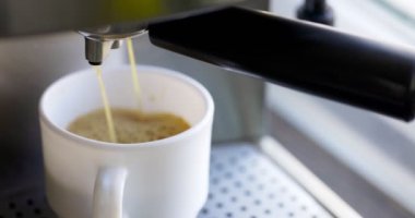 Kahve espresso ya da kahve makinesinde rigerto yapmak. Evde sıcak espresso yapıyorum. Köpüklü kahve. Beyaz bardakta espresso. Kahvaltıda içecek.