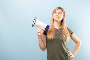 Mavi arka planda megafon tutan genç bir kadın. Konuşma ve duyuru kavramı, pazarlama veya satış fikri.
