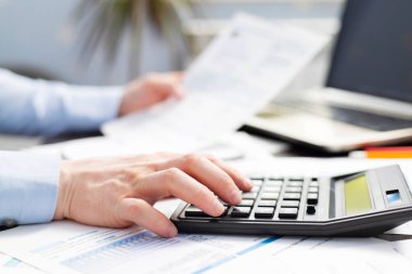 Faturaları ve hesap makinesi olan adam. İşadamı ofisteki masada hesap makinesini kullanarak faturaları hesaplıyor. Finansal muhasebe kavramı.