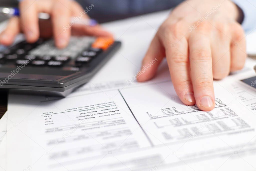 Man with bills and calculator. Businessman using calculator to calculate bills at the table in office. Financial accounting concept.