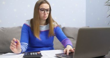 Ev faturalarını hesaplamak için hesap makinesi kullanan bir kadın, vergi ödemek için evrak işi yapan bir kadın.