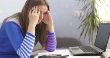 Stresli genç esmer kadın evde oturup aile mali sorunları yüzünden hayal kırıklığına uğramış ev işleriyle uğraşıyor. Üzgün kadın para borcu yüzünden hayal kırıklığına uğradı, internette faturalarını ödüyor.