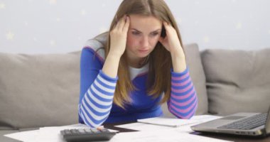 Stresli genç esmer kadın evde oturup aile mali sorunları yüzünden hayal kırıklığına uğramış ev işleriyle uğraşıyor. Üzgün kadın para borcu yüzünden hayal kırıklığına uğradı, internette faturalarını ödüyor.