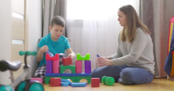 母亲和儿子一起玩彩色立方体 坐在家里的地板上 家人在孩子们的房间里呆着 — 图库视频影像