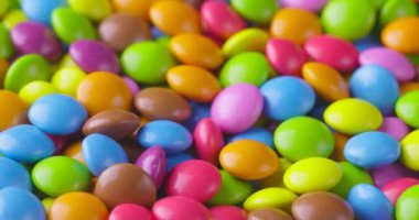 Yuvarlak renkli çikolata şekerlemeleri yavaş çekimde, Dragee. Döndürme ve düşme çok renkli çikolata şekerlemeleri