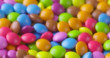 Yuvarlak renkli çikolata şekerlemeleri yavaş çekimde, Dragee. Döndürme ve düşme çok renkli çikolata şekerlemeleri
