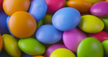 Yuvarlak renkli çikolata şekerlemeleri yavaş çekimde, Dragee. Döndürme ve düşme çok renkli çikolata şekerlemeleri