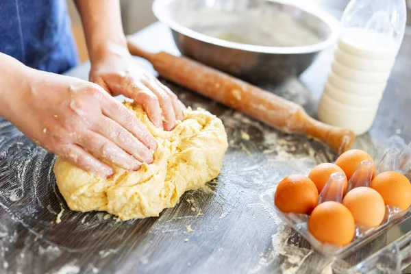 Dişi eller merdane, yumurta ve süt şişesinin yanındaki ahşap masada pişirmek için hamur yapıyor. Mutfak, yemek pişirme, pişirme konsepti