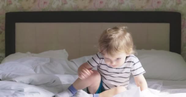 Kıvırcık Saçlı Tişörtlü Şortlu Bir Çocuk Sabahları Yatakta Zıplıyor — Stok video