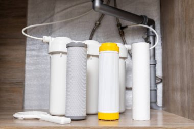 House water filtration system. Installation or replacement of water purification filters under kitchen sink in cupboard. Clear water concept.