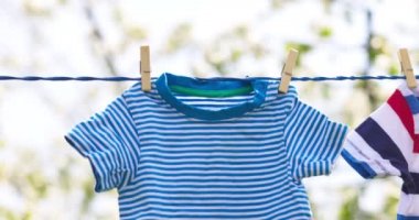 Clean clothes on rope outdoors on laundry day. Colorful t-shirts hanging on a laundry line against blue sky