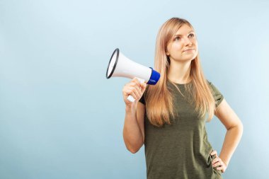 Mavi arka planda megafon tutan genç bir kadın. Konuşma ve duyuru kavramı, pazarlama veya satış fikri.