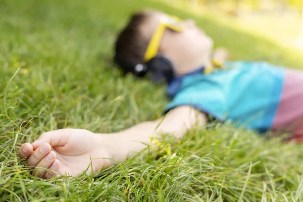 Счастливый Мальчик Солнечных Очках Лежащий Траве Слушающий Музыку Наушниках Солнечный — стоковое фото