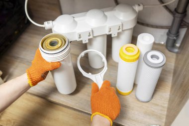 Plumber installs or change water filter. Replacement aqua filter. Repairman installing water filter cartridges in a kitchen. Clean water at home.