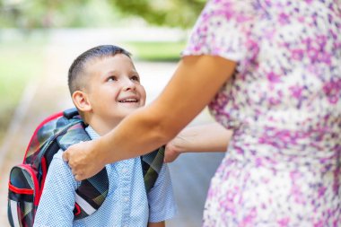 Back to school. Mother saying goodbye to her son as he leave for School. Schoolboy is ready go to school. First day at school.